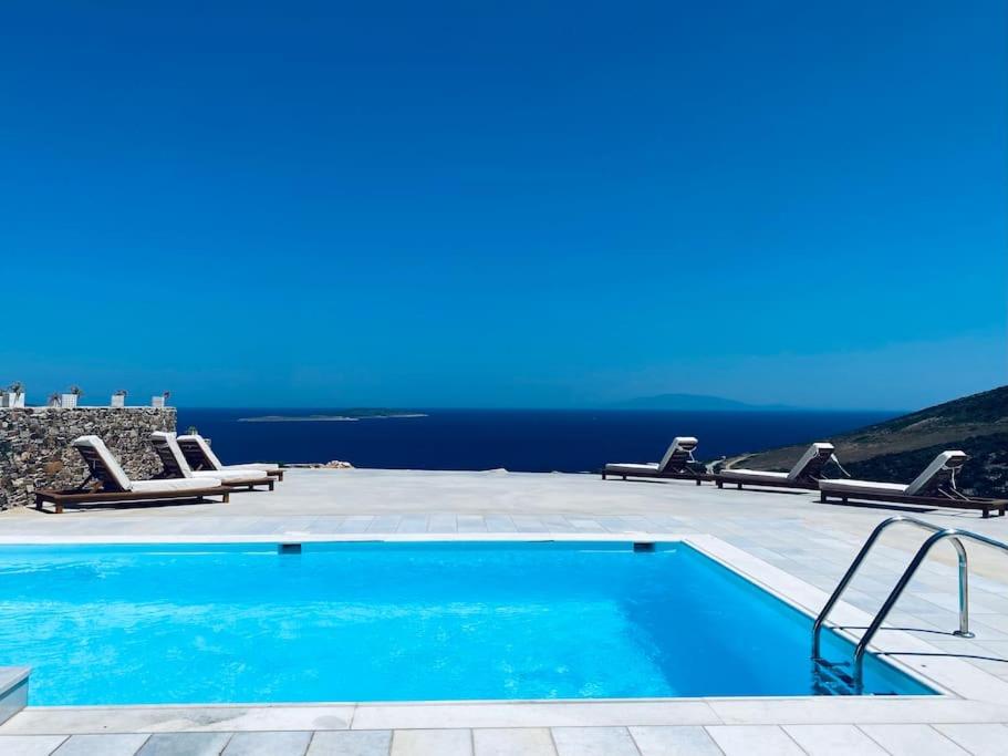 a swimming pool with chairs and a view of the ocean at Artemis Sky Villa in Antiparos