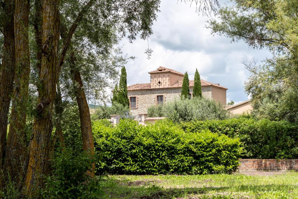 a house in the background with trees and bushes at Agriresort Tenuta Macchiacupa in Ariano Irpino