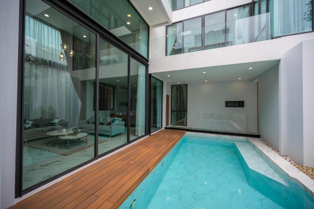 - une piscine intérieure dans une maison aux parois de verre dans l'établissement Poolvilla Near Nimmanheim - KING BED 3BR, à Chiang Mai