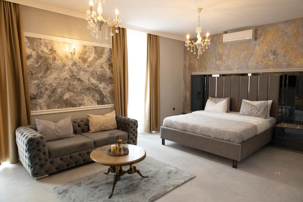 ein Schlafzimmer mit einem Bett, einem Sofa und einem Tisch in der Unterkunft All Elevens 11 Apartments in Bitola