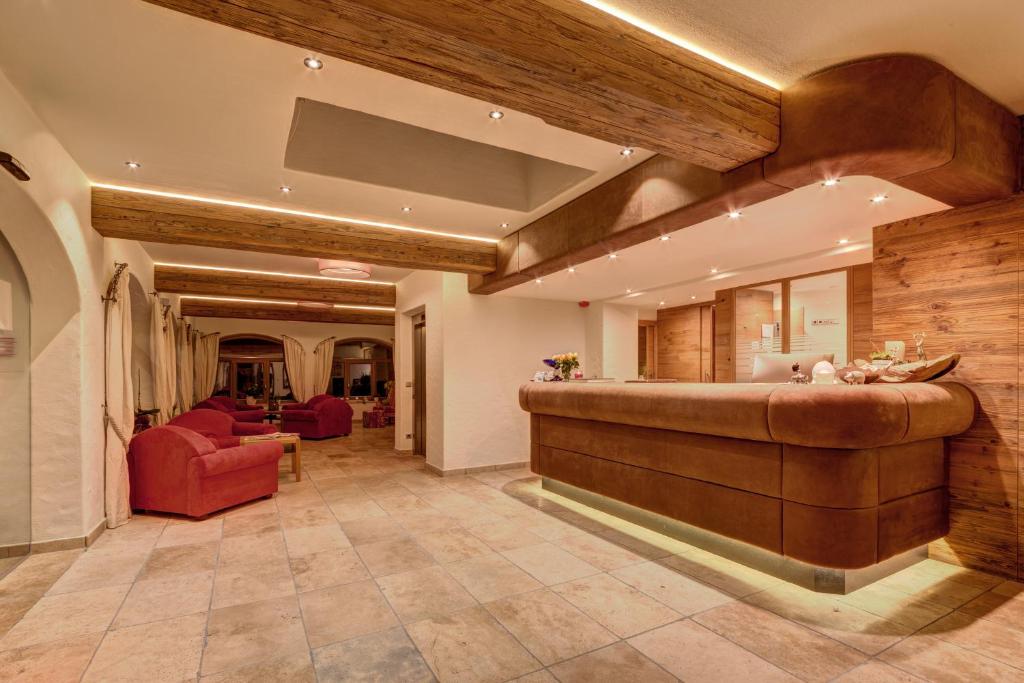 eine große Lobby mit einer Bar und einem roten Stuhl in der Unterkunft Hotel am Schloss in Goldegg