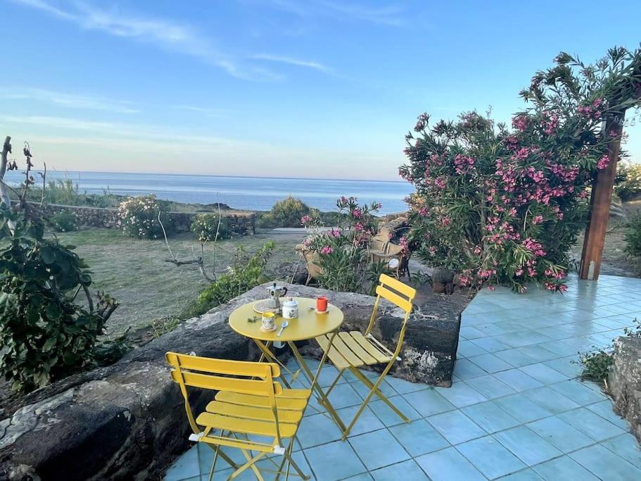 a table and chairs on a patio with a view of the ocean at Casa Nocilla, un dammuso sul mare! in Pantelleria