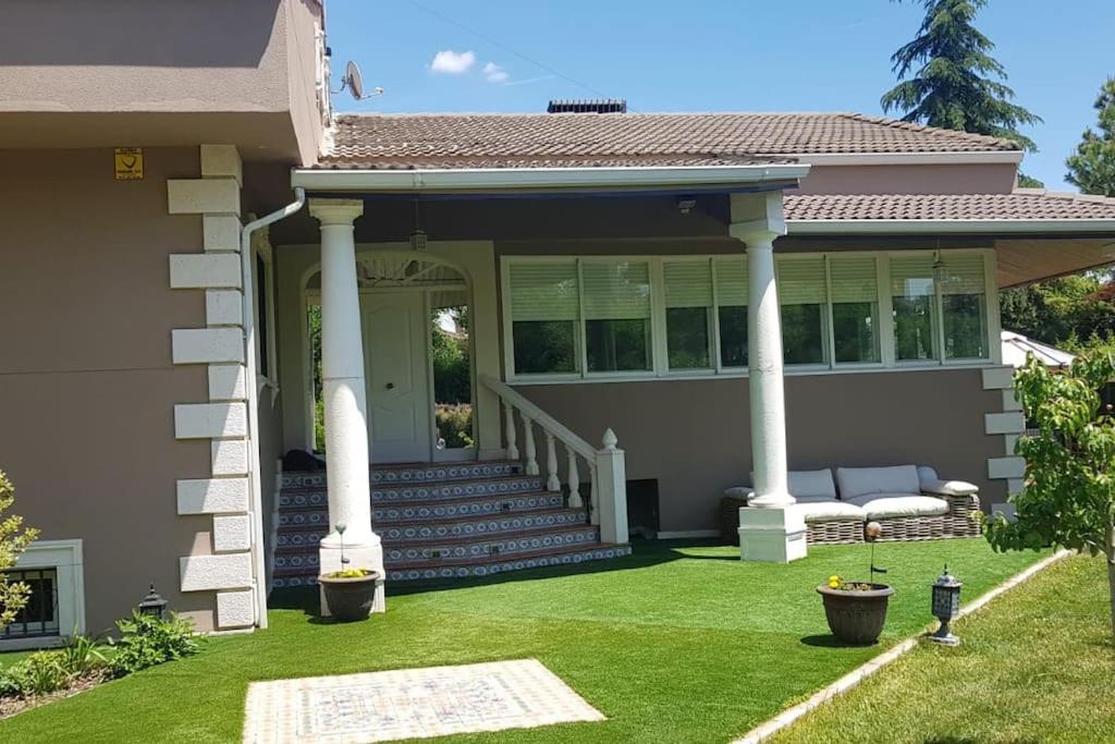 a home with a porch with columns and grass at Casa de lujo con piscina privada, cerca de Madrid in Villalbilla