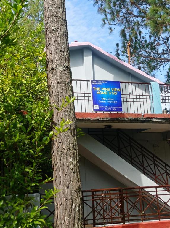 a sign on the side of a building next to a tree at The Pine View Home Stay in Almora