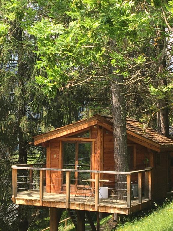 een boomhut met een terras in een bos bij la Cabane dans les Arbres in Saint-Jean-dʼAulps