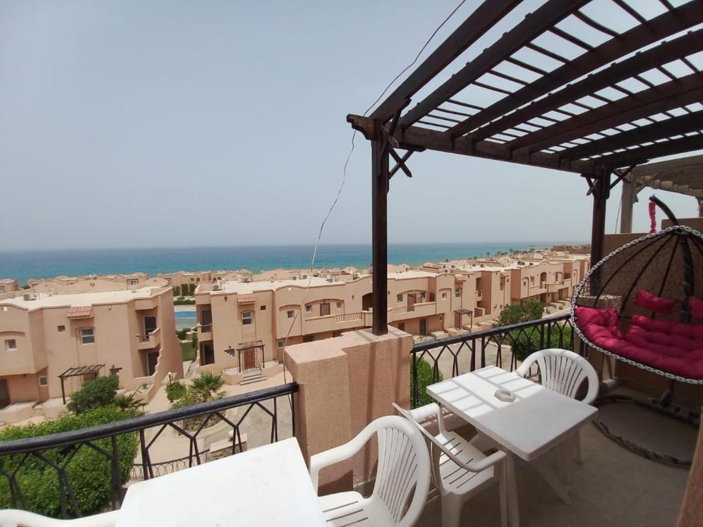 a balcony with tables and chairs and a view of a city at شالية علي البحر بالعين السخنة بقرية امباير ريزورت in Ain Sokhna
