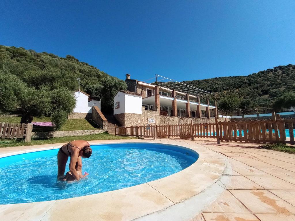 una persona in una piscina con una casa sullo sfondo di Casa Rural Agua de Azahar Chimenea a Zahara de la Sierra