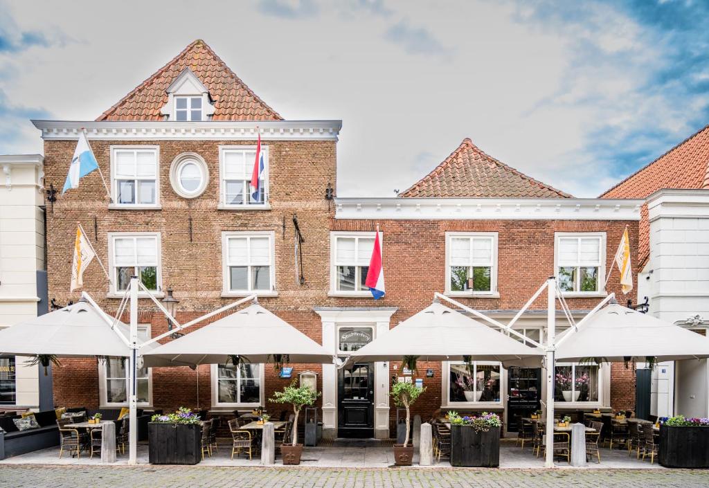 een groot bakstenen gebouw met parasols ervoor bij Hotel Restaurant De Keurvorst in Ravenstein