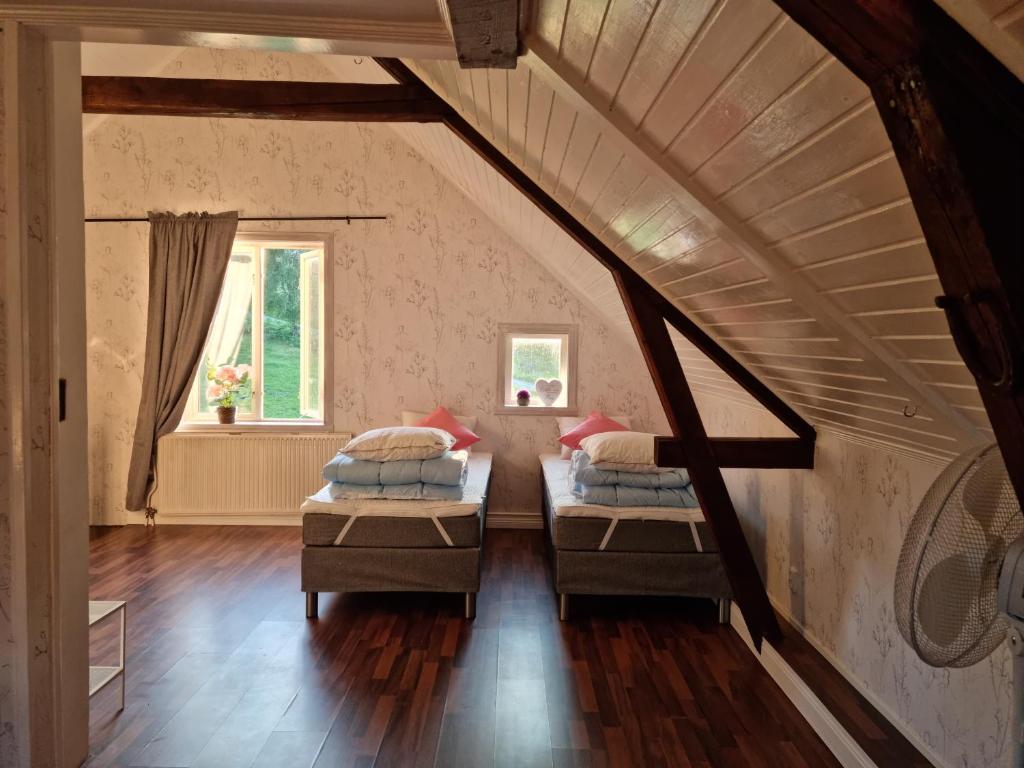 een zolderkamer met 2 bedden en een trap bij Charmigt hus på landet nära till bad in Strömstad