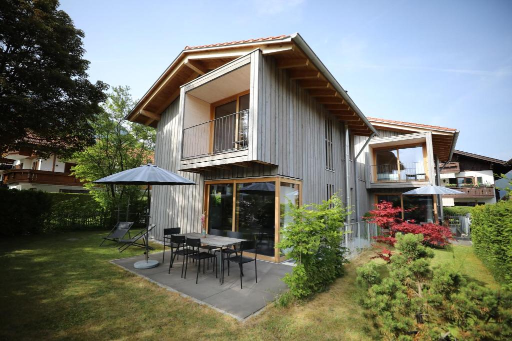 una casa con mesa, sillas y sombrilla en Traumferienhaus 2 mit Sauna und Bergblick, en Garmisch-Partenkirchen