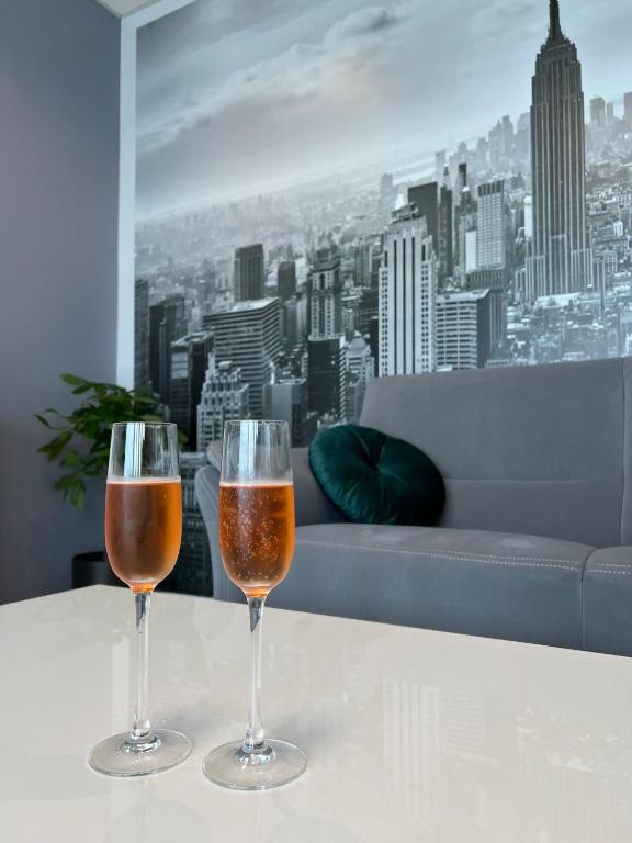 two wine glasses sitting on a table in front of a window at Krasta Home apartament Parking & With CITY & RIVER VIEW in Riga