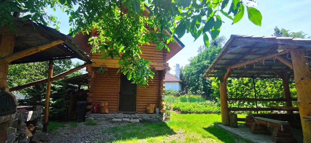 a small wooden cabin in a yard with a tree at Cabana Colt de Rai in Ocna Şugatag
