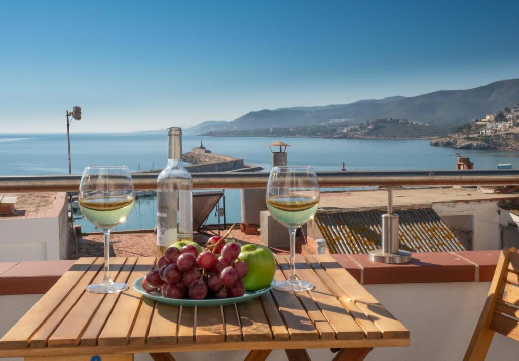 un tavolo con due bicchieri di vino e un piatto di frutta di Casas del Castillo Peñíscola-Intramuros Suites a Peñíscola
