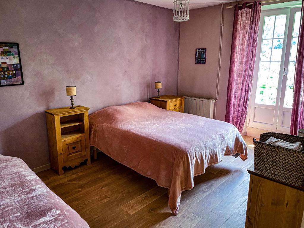 een slaapkamer met een bed, 2 tafels en een raam bij Lisons des Sources in Nans-sous-Sainte-Anne