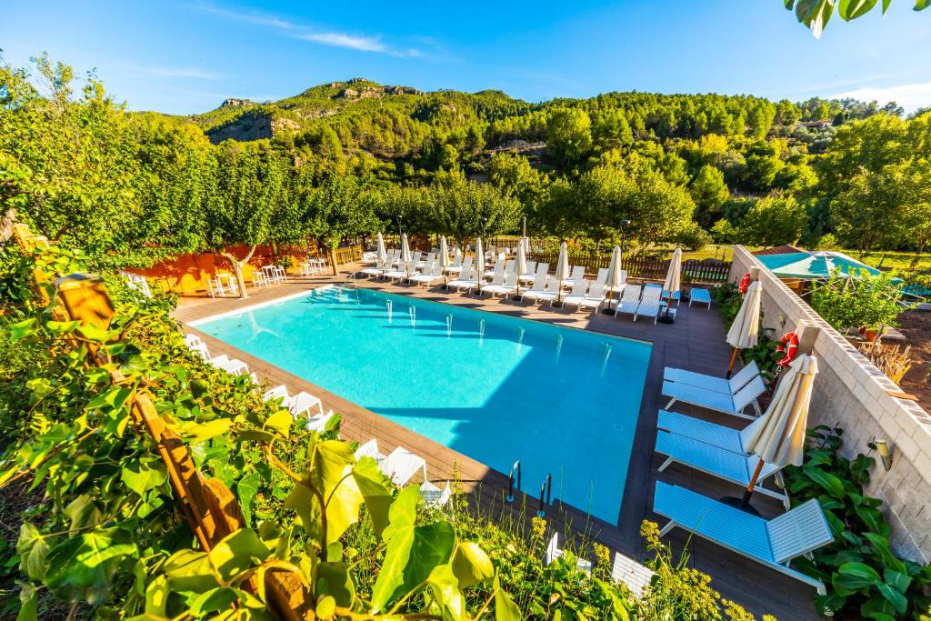 una piscina al aire libre con sillas y sombrillas en Hotel Rosaleda del Mijares, en Montanejos
