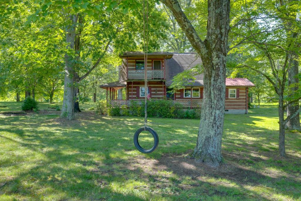 a tire swing in front of a log house at Family-Friendly Afton Cabin with Spacious Yard! in Greeneville