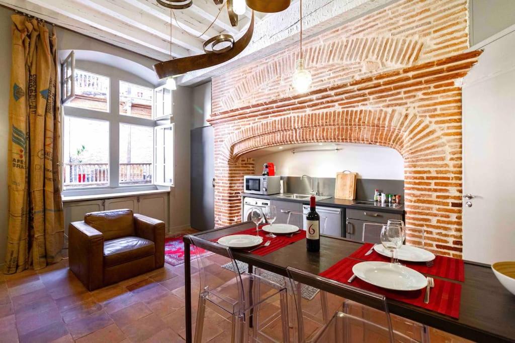 a kitchen with a table and a brick wall at Duplex climatisé dans un monument historique in Toulouse