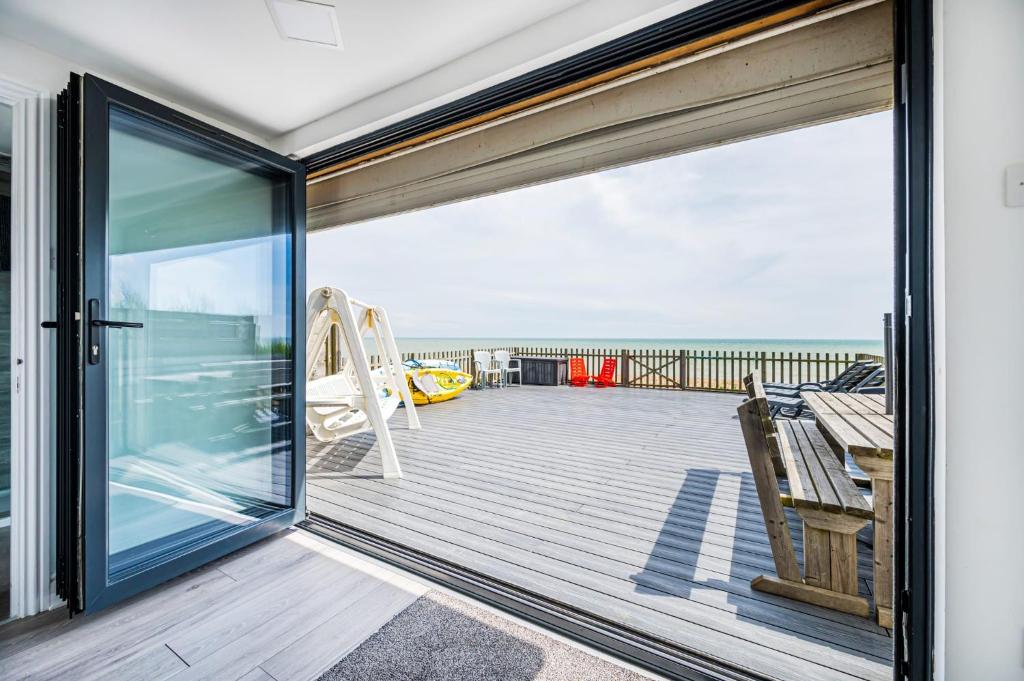 a sliding glass door on a deck with a view of the ocean at Family Beachfront Bliss Sleeps 10 in Pevensey