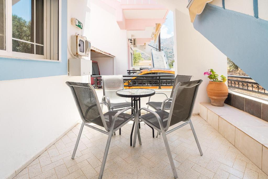 a small table and chairs on a balcony with a window at Olympus Tilos Apt double A2 in Livadia