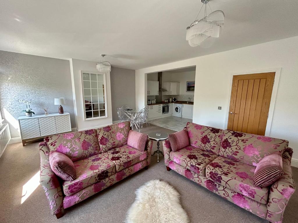 a living room with pink couches and a kitchen at Apartment 33 Lytham in Lytham St Annes