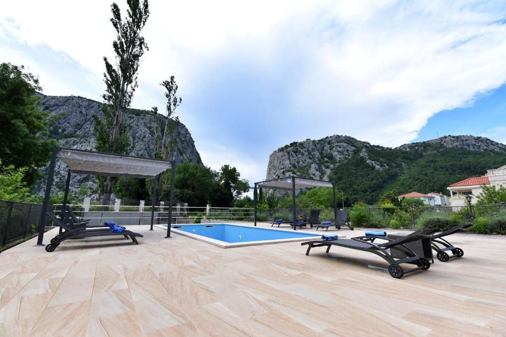 een zwembad met 2 stoelen en een pooltafel bij Villa Sophia with private swimming pool near the beach! in Zakučac