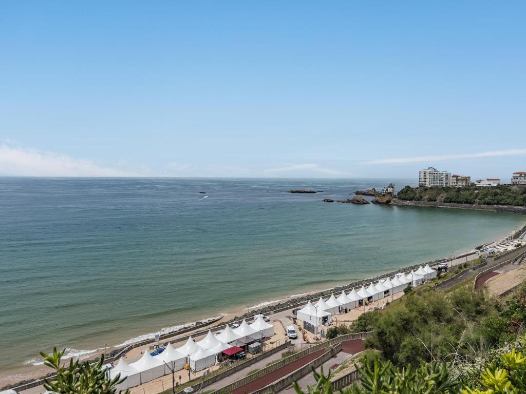 - une vue aérienne sur une plage avec des parasols blancs dans l'établissement Reine de Serbie, à Biarritz