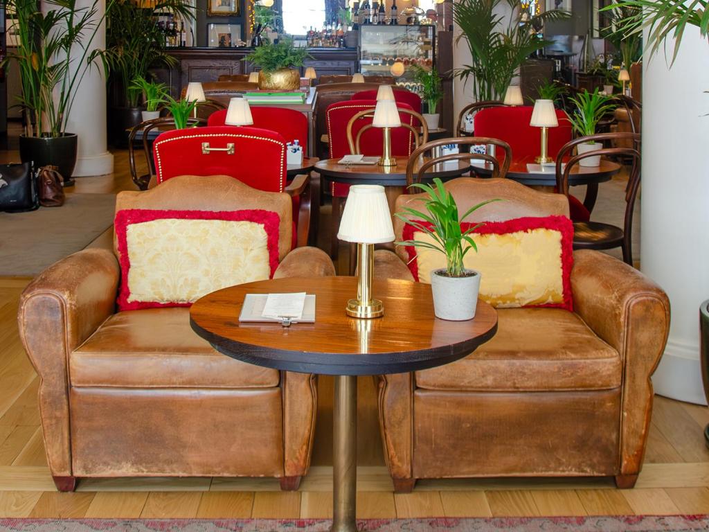 A central lounge seating area with leather sofas, red chairs, plants and small lamp-lit tables.