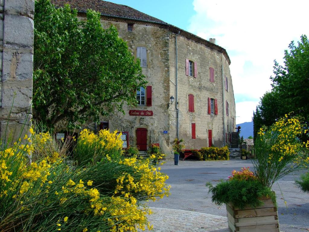 un viejo edificio de piedra con flores delante en Château de Rosans en Rosans