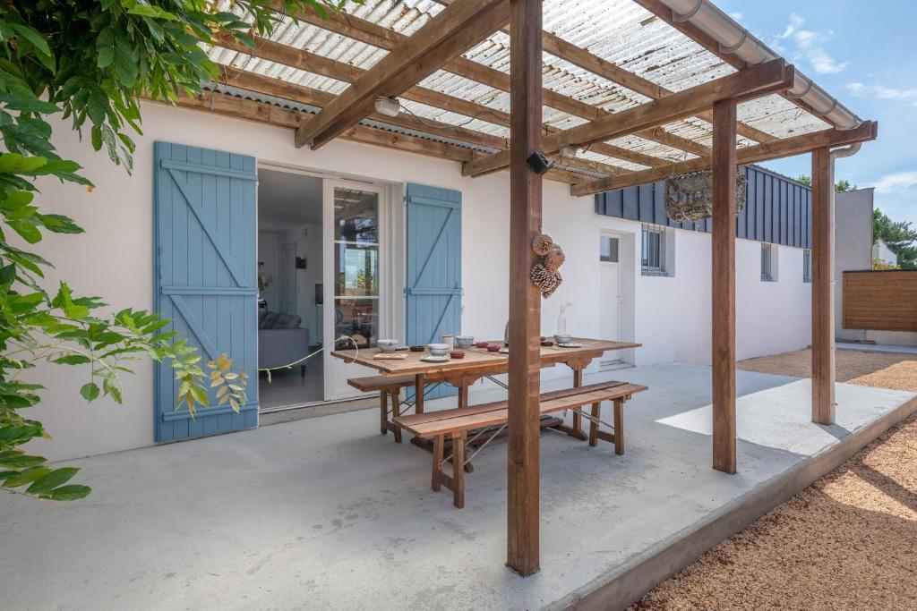 une terrasse avec une table en bois et une pergola en bois. dans l'établissement Escapade au Croisic!, au Croisic