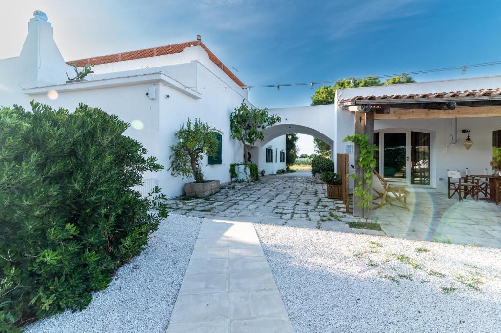 a white house with a courtyard and a patio at Pozzo Traverso Casale in Leporano Marina