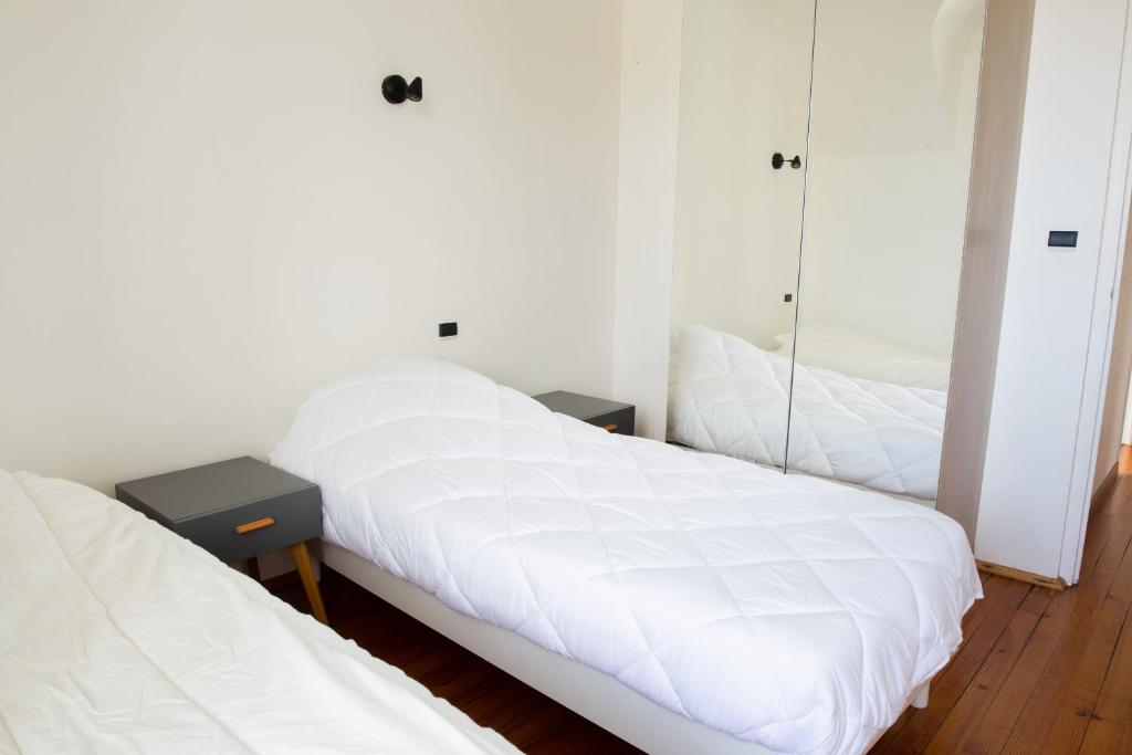 a bedroom with two beds with white sheets and a mirror at Escapade au calme tout pres de la plage in Penmarch