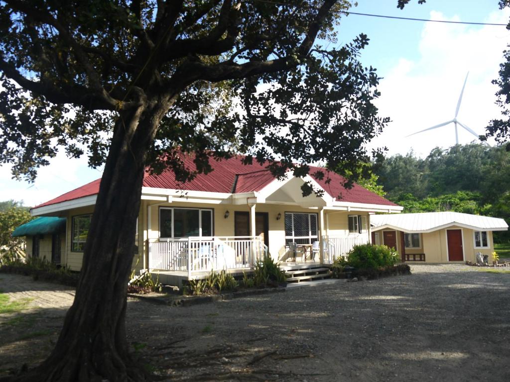 een geel huis met een rood dak en een boom bij Villa in Pagudpud