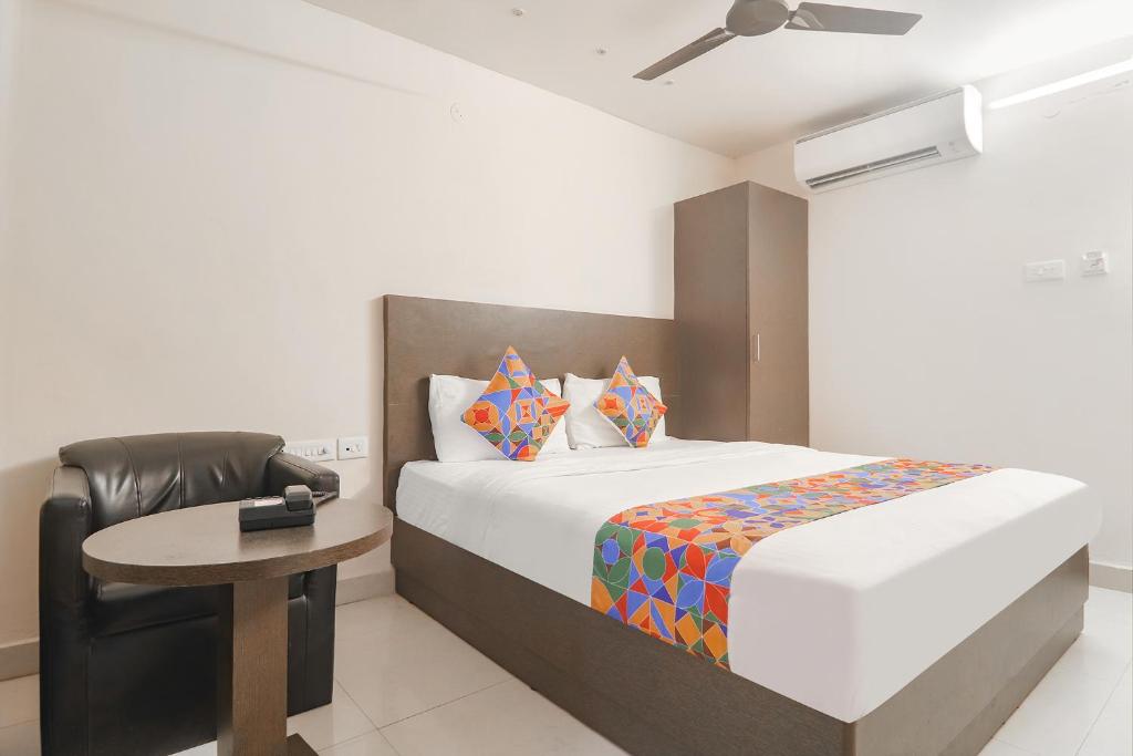 a bedroom with a bed and a chair and a table at FabHotel Akshara Innotel in Visakhapatnam