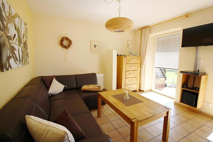 ein Wohnzimmer mit einem braunen Sofa und einem Tisch in der Unterkunft Seestern in Bliesdorf