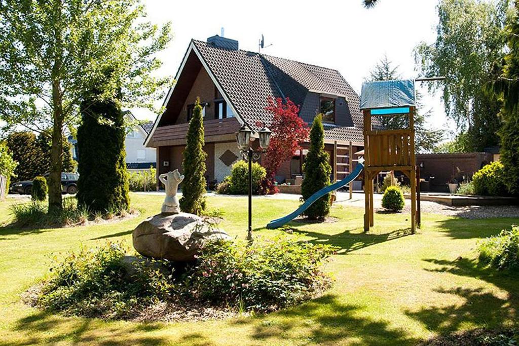 einen Hof mit einem Spielplatz mit Rutsche und einem Haus in der Unterkunft Traumgarten in Harmsdorf