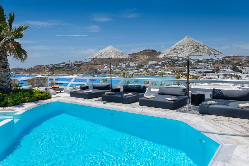 a swimming pool with chairs and umbrellas in a resort at Deliades Hotel in Ornos