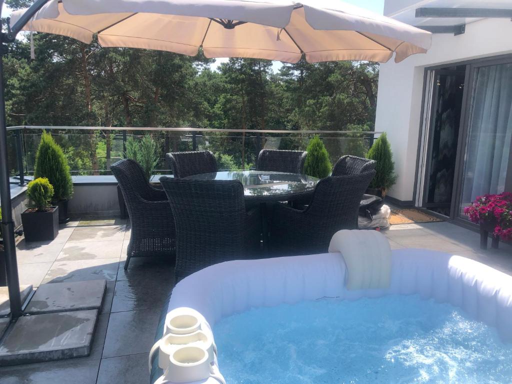 un patio avec une table, des chaises et un parasol dans l'établissement Apartament Business&Living No 73 z prywatnym jacuzzi zewnętrznym -od maja do września- Nad Zalewem w Cedzynie i miejscem parkingowym, à Cedzyna