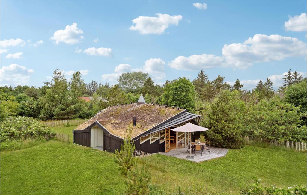 a small house with a thatched roof in a field at Awesome Home In Strandby With 2 Bedrooms And Wifi in Strandby