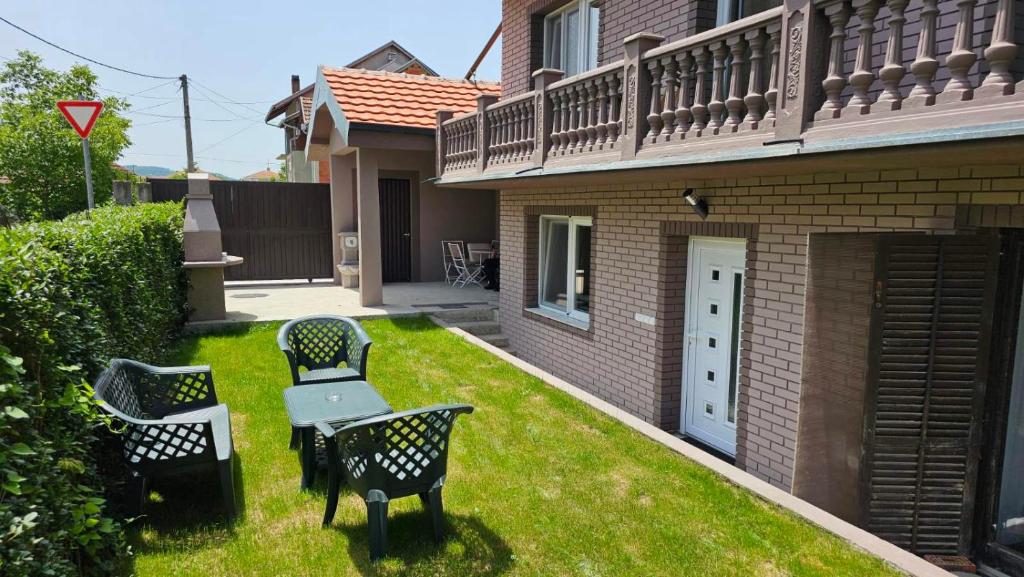 a yard with chairs and a table in the grass at Garden apartmani in Jagodina