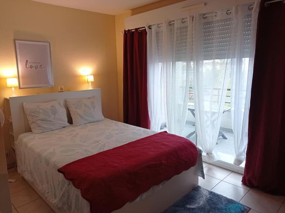 a bedroom with a bed and a large window at Studio sur la plage des Dagueys in Libourne
