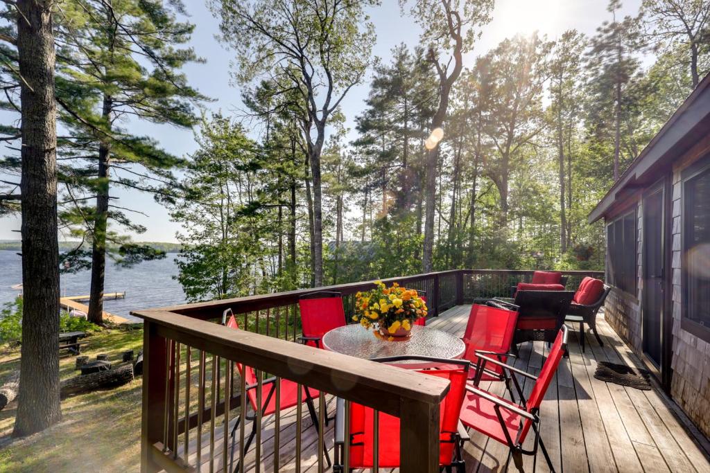 una terraza con sillas rojas y una mesa con flores. en Waterfront Maine Vacation Rental with Private Dock, en Orono