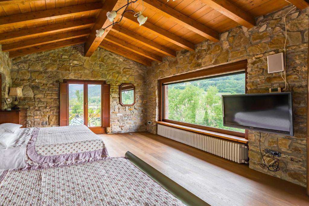 una camera da letto con un grande muro in pietra e una TV a schermo piatto di Agriturismo Il Salice a Tizzano Val Parma