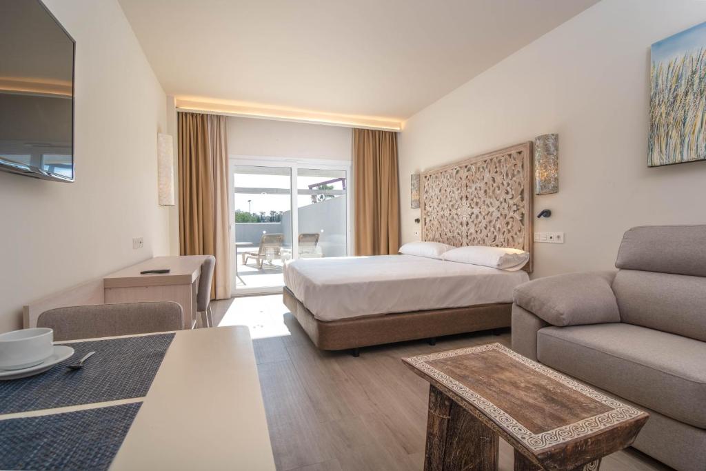 Aljarafe Suites by QHotels في Gelves: غرفه فندقيه بسرير واريكه