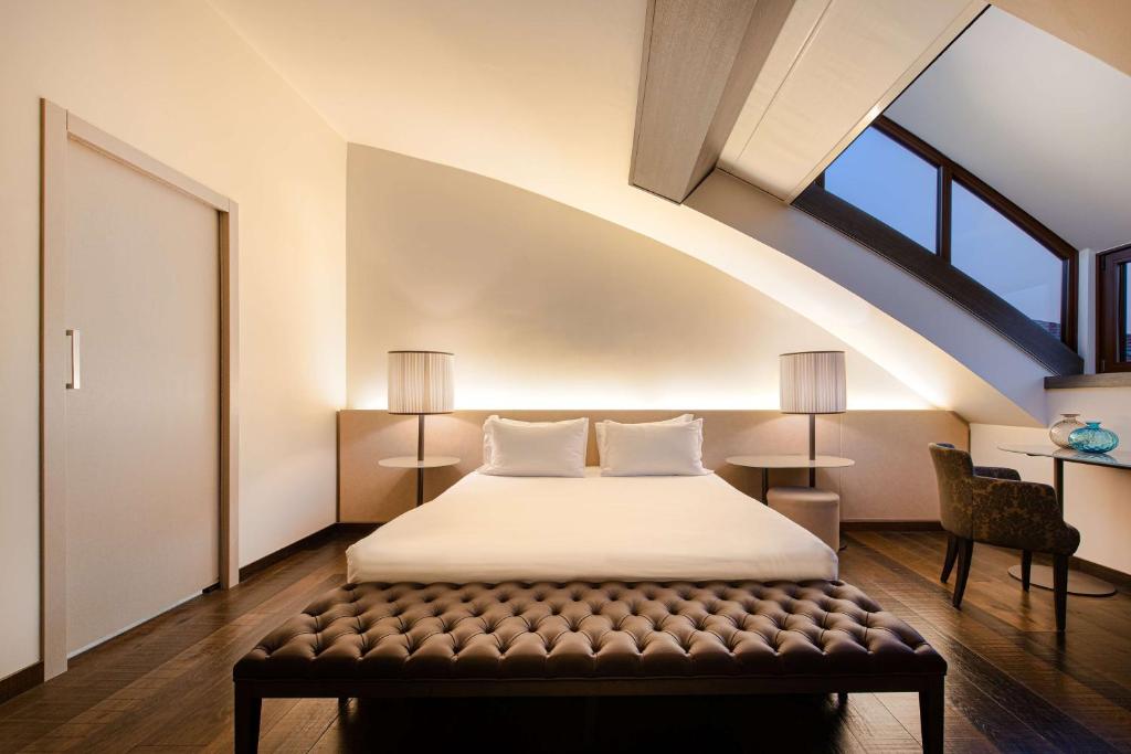 a bedroom with a bed with a bench in it at Hyatt Centric Murano Venice in Murano
