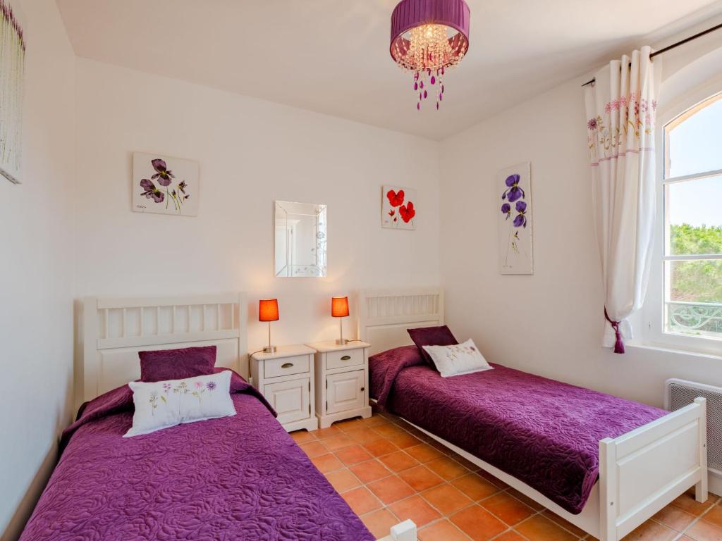 two beds in a bedroom with purple sheets and a chandelier at Holiday Home La Bastide Rose by Interhome in Sainte-Maxime