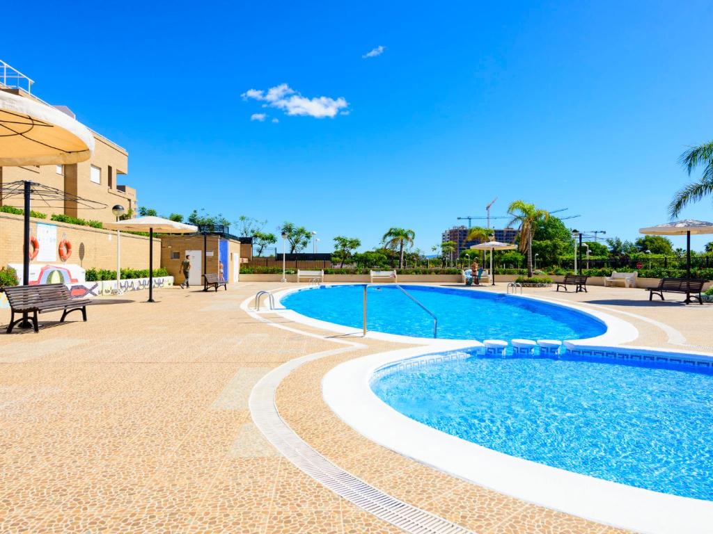 a swimming pool in a resort with a blue sky at Apartment Jardines del Mar I-1 by Interhome in El Borseral