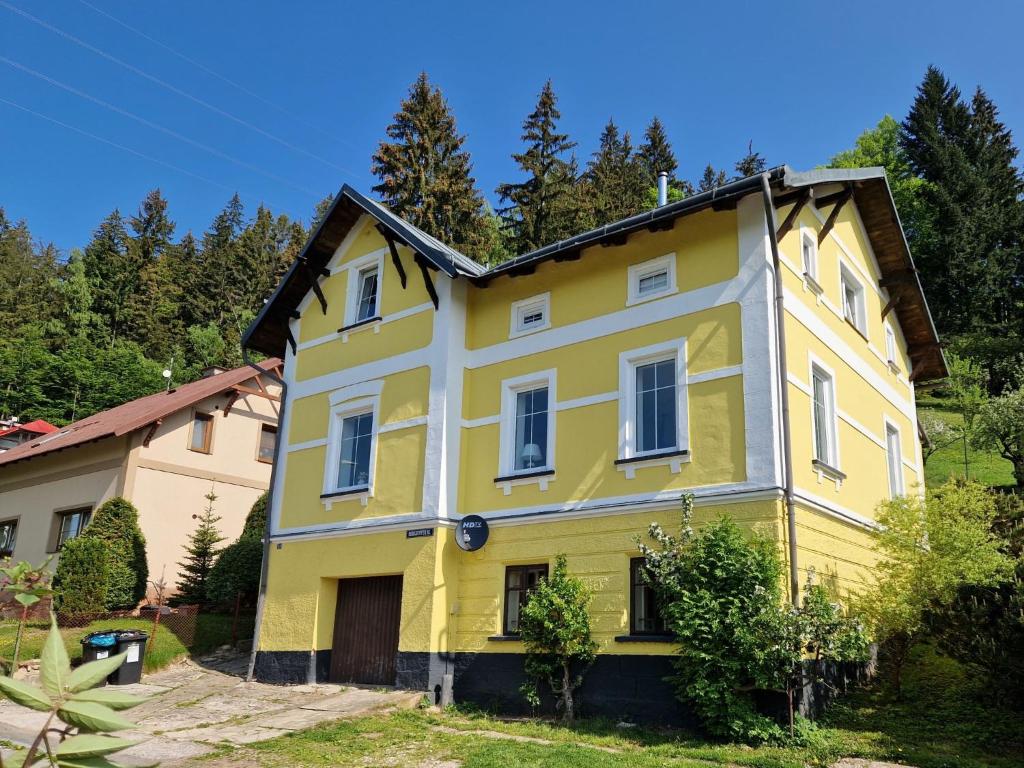 una casa amarilla y blanca con árboles en el fondo en Villa Svoboda na Úpou by Interhome, en Svoboda nad Úpou