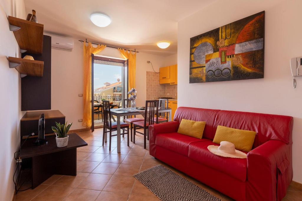 a living room with a red couch and a dining room at KaRol Casa Vacanze in Alghero