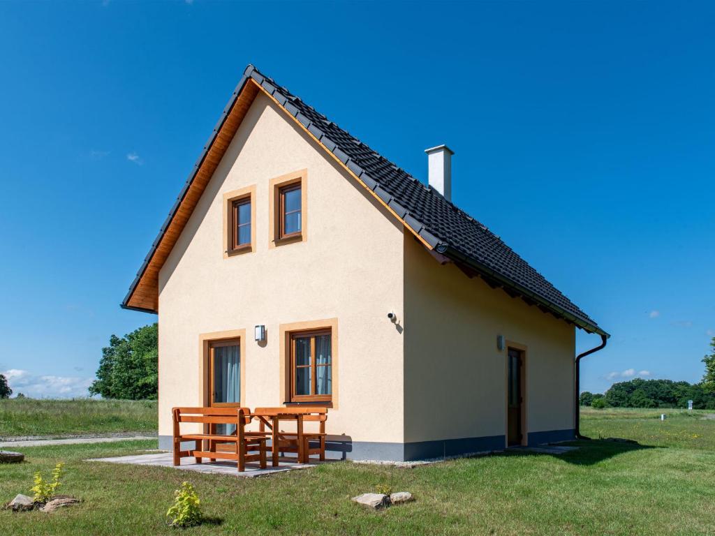 una pequeña casa blanca con un banco y una mesa en Holiday Home Cilka 2 by Interhome, en Stráž nad Nežárkou