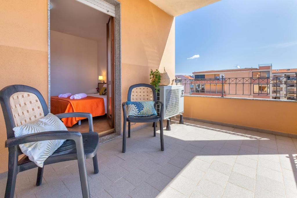 a balcony with two chairs and a bed on a building at KaRol Casa Vacanze in Alghero
